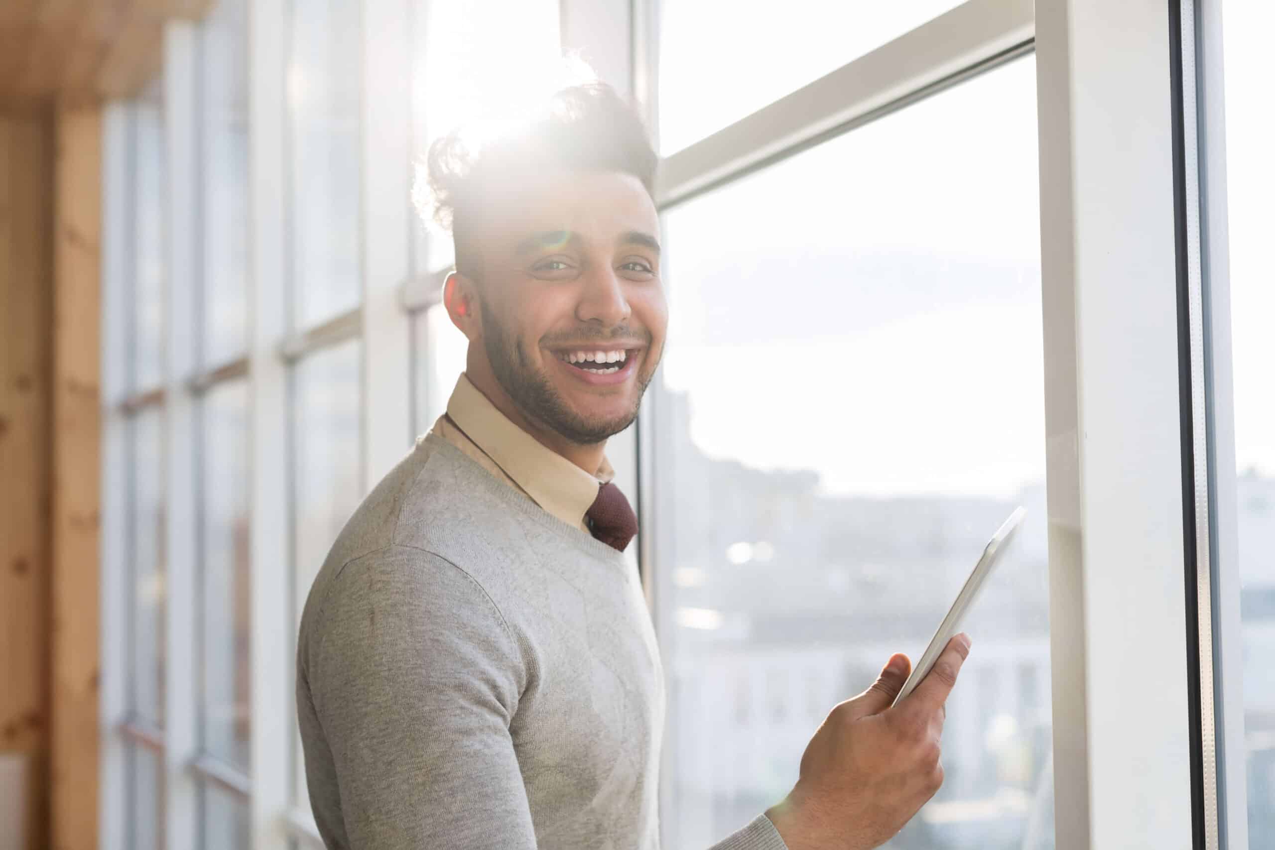 Man looking out the window with a sun ray and smiling pearly white teeth