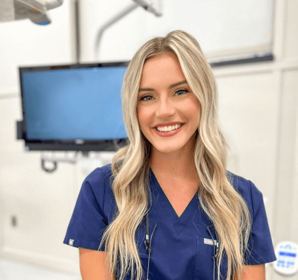 Lexi, dental hygienist who does teeth cleanings standing in front of screen
